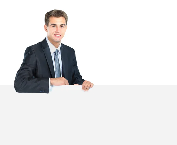Feliz sorridente jovem homem de negócios mostrando placa em branco — Fotografia de Stock