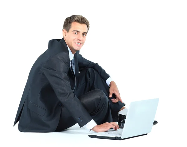 Isolated seated young businessman using a laptop — Stock Photo, Image