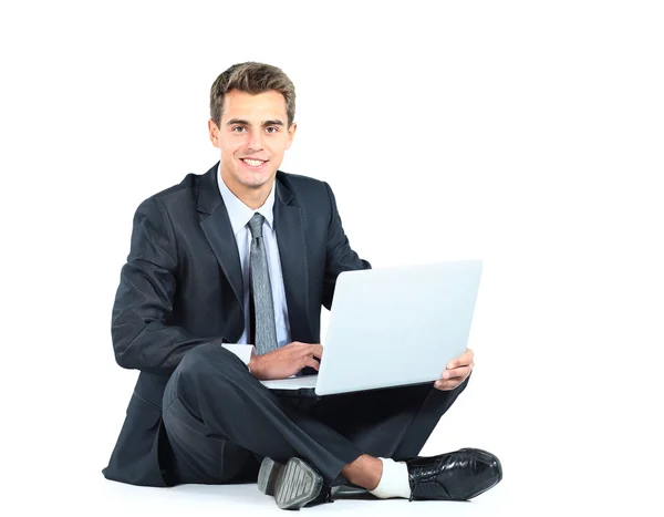 Na białym tle siedzi młody biznesmen za pomocą laptopa — Zdjęcie stockowe