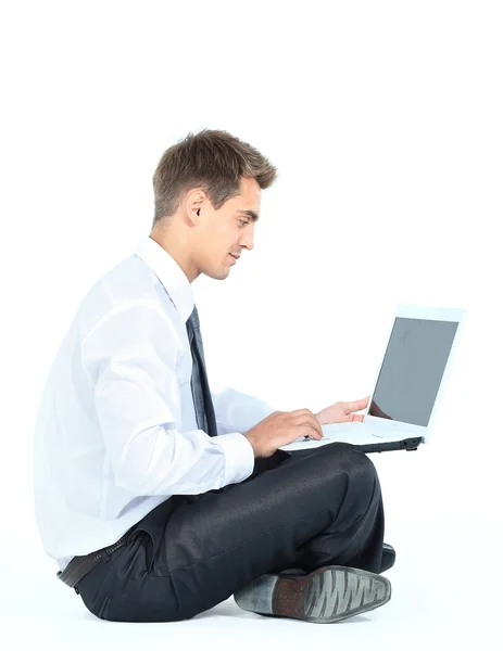 Bir dizüstü bilgisayar kullanarak izole oturan genç iş adamı — Stok fotoğraf