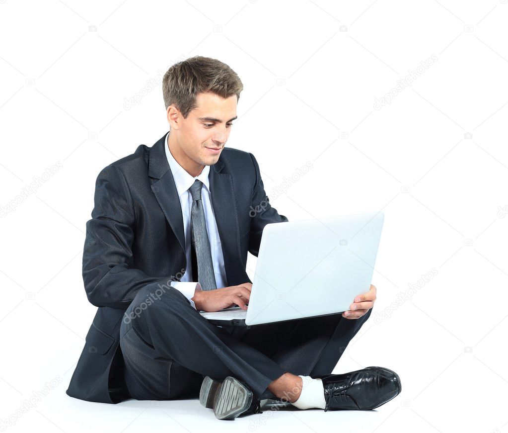 Isolated seated young businessman using a laptop