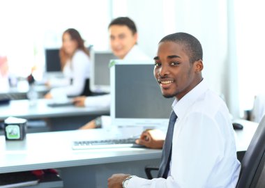 Portrait of a happy African American entrepreneur displaying computer laptop in office clipart