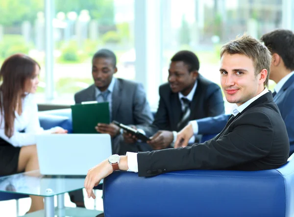 Jovem empresário confiante a assistir a uma reunião com os seus colegas — Fotografia de Stock