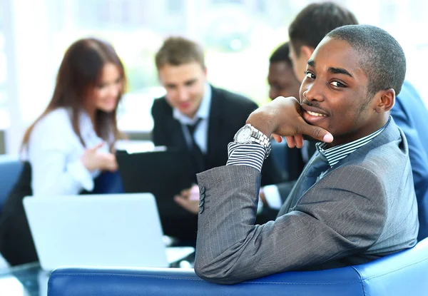 Portret van Afro-Amerikaanse zakenman lachend met executives werken op achtergrond — Stockfoto
