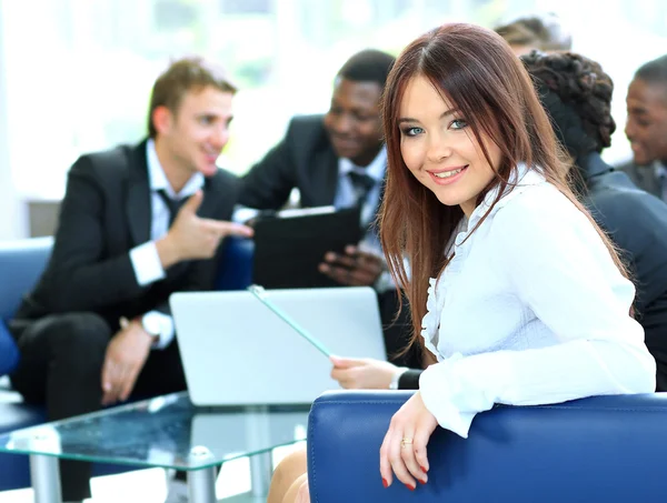 Крупный план красивой молодой предпринимательницы, улыбающейся на встрече со своими коллегами на заднем плане — стоковое фото