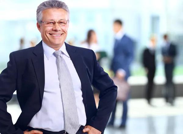 Uomo d'affari di successo in piedi con il suo personale in background in ufficio — Foto Stock