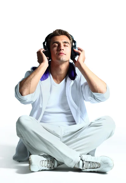 Portret van een ontspannen jonge man luisteren naar muziek op hoofdtelefoon tegen witte achtergrond — Stockfoto