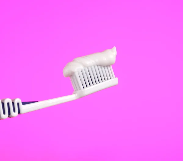 Escova de dentes com pasta de dentes no fundo rosa — Fotografia de Stock