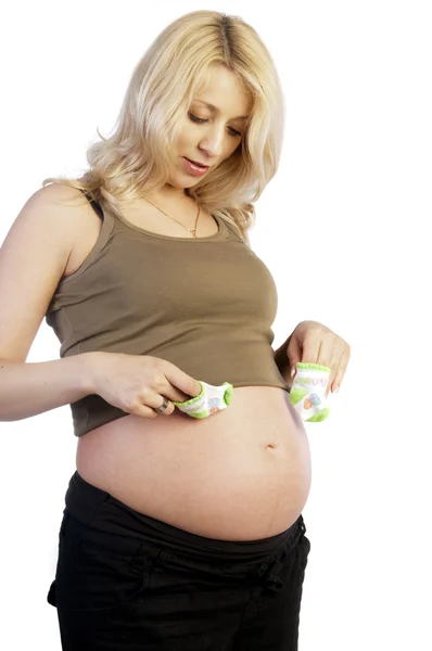 Pregnant woman holding baby's socks on her belly — Stock Photo, Image