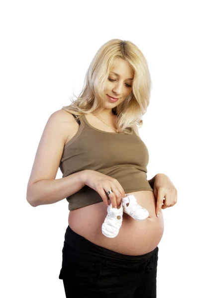 Mulher grávida segurando botas do bebê em sua barriga — Fotografia de Stock