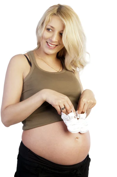 Pregnant woman holding baby's bootees on her belly — Stock Photo, Image