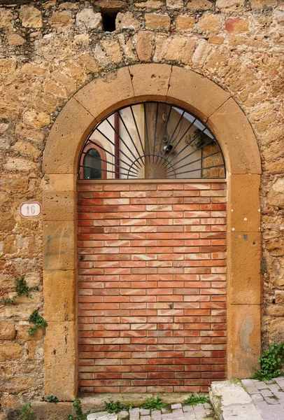 Старая арочная дверь, заблокированная кирпичной стеной — стоковое фото