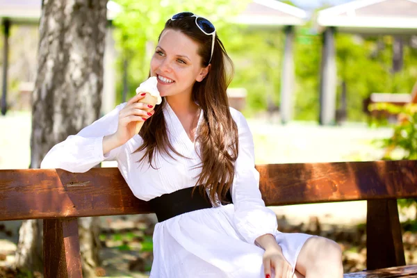 Una donna sorridente sta mangiando un gelato — Foto Stock