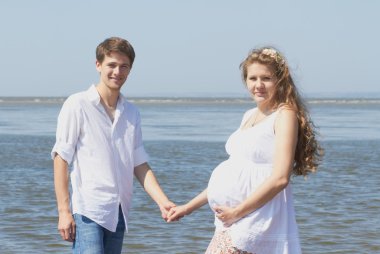 Happy pregnant girl and her loving husband clipart