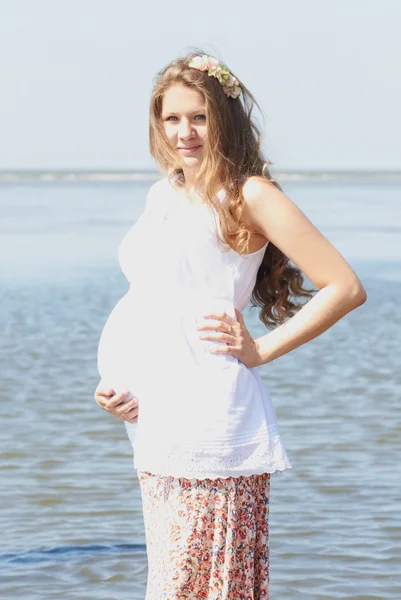 Счастливая беременная девушка на пляже — стоковое фото