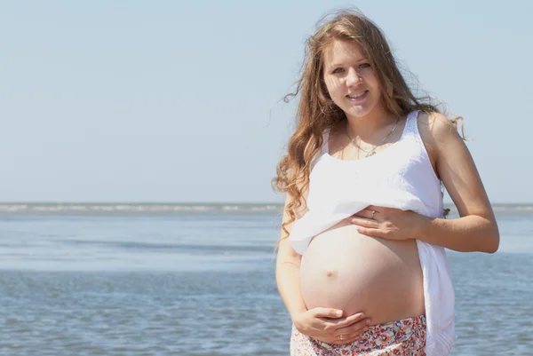 Счастливая беременная девушка на пляже — стоковое фото