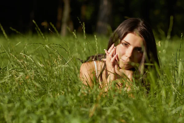 Piękna, młoda dziewczyna leży w zielonej trawie — Zdjęcie stockowe