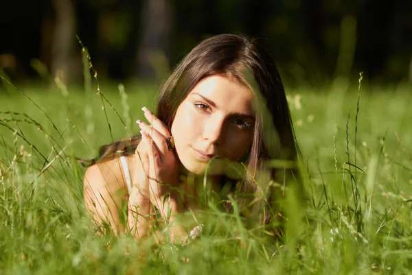Mooi meisje liggen in groene gras — Stockfoto