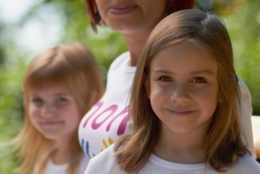 Cute little girls with their mom outdoors clipart