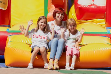Mother and her daughters sitting on bouncing castle clipart