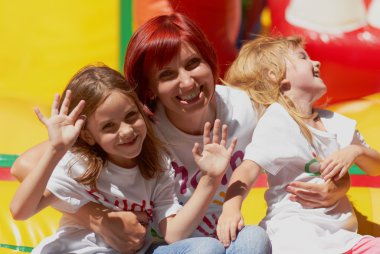 Mother and her daughters having fun on jumping castle clipart