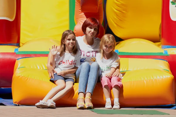 Mother and her daughters sitting on jumping castle — Stock Photo, Image