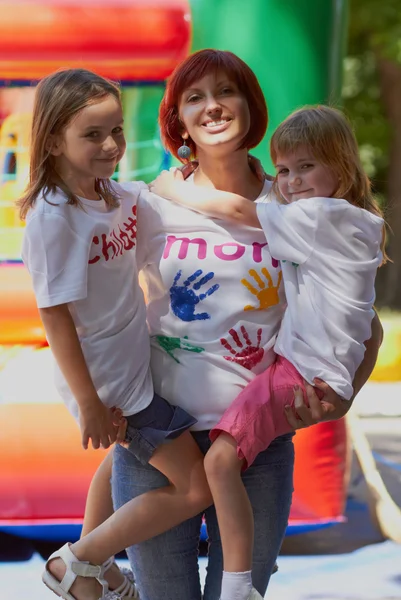 Мать держит дочерей в руках на улице — стоковое фото