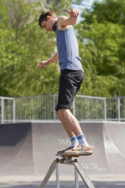 Skater doing 50-50 grind on fun-box in skatepark clipart