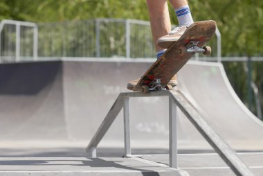Skater doing nose grind on fun-box in skatepark clipart