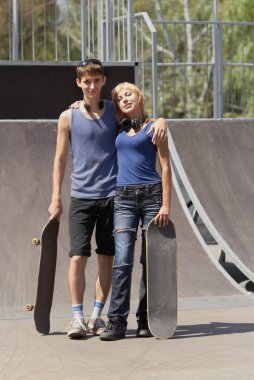 Teen skaters with boards in skatepark clipart