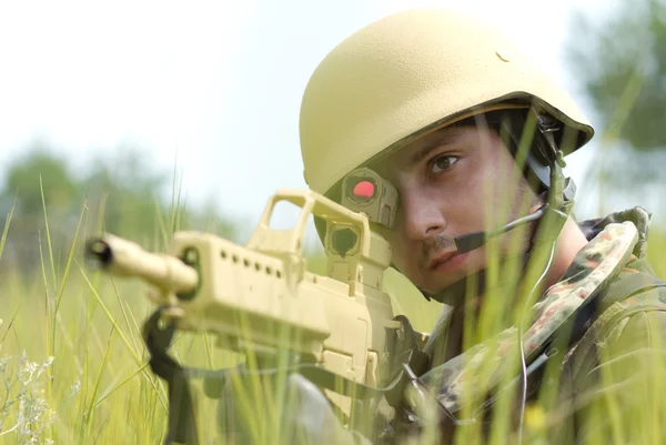 Joven soldado en el casco apuntando — Foto de Stock