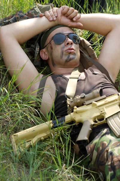 Voják bere zbytek ležet trávě — Stock fotografie