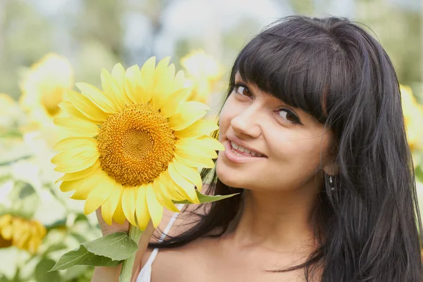 Lachende meisje met zonnebloem buitenshuis — Stockfoto