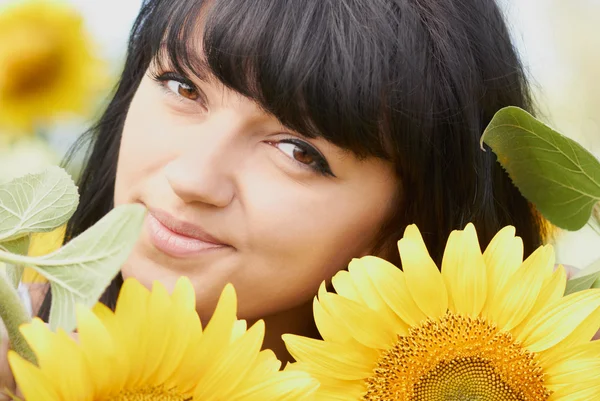 Jong meisje met zonnebloemen buitenshuis — Stockfoto