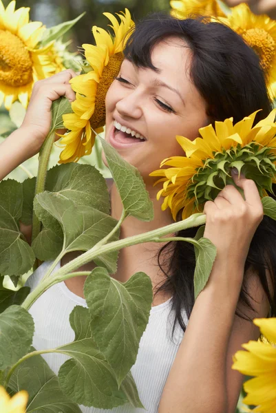 Mädchen spielt mit Sonnenblumen im Feld — Stockfoto