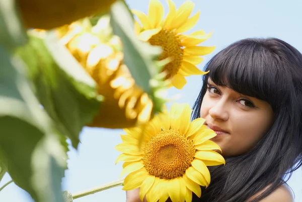 Mädchen mit Sonnenblume unter blauem Himmel — Stockfoto