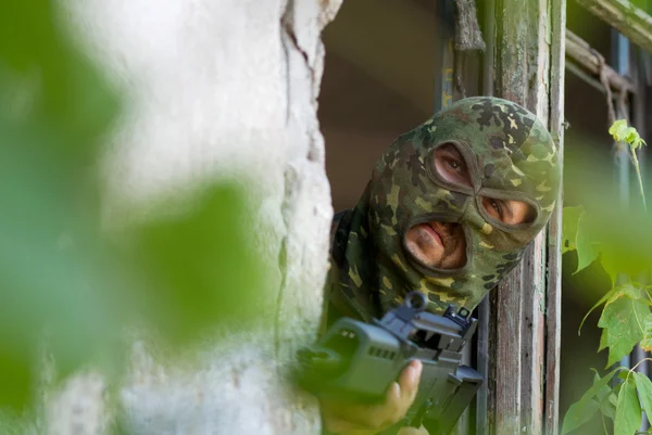 Armed terrorist looking out of window — Stock Photo, Image