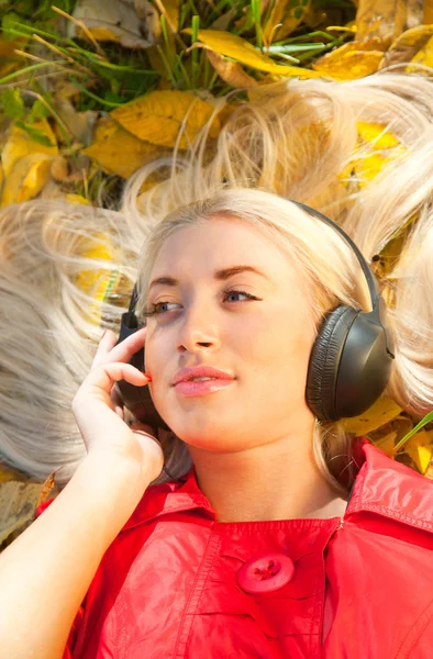 Дівчина з навушниками в осінньому парку — стокове фото