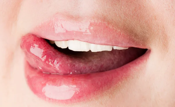 Junge Frau leckt ihre rosa Lippen — Stockfoto