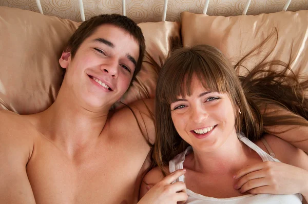 Portret szczęśliwy młoda para zabawy na łóżku — Zdjęcie stockowe