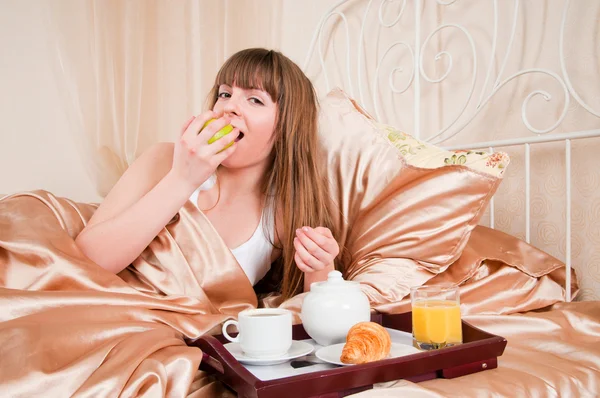 Kobieta jedzenie śniadanie i picia kawy w łóżku. młoda kobieta s — Zdjęcie stockowe