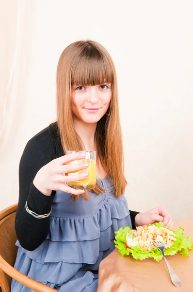 Młoda kobieta siedzi przy stole śniadanie, picie pomarańczowy j — Zdjęcie stockowe