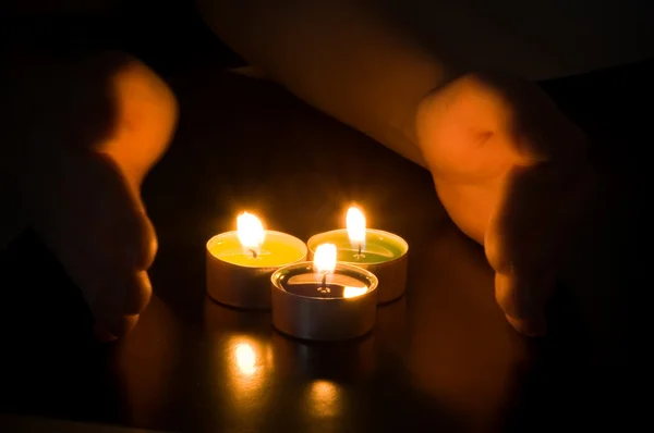 Руки забиті навколо свічки — стокове фото