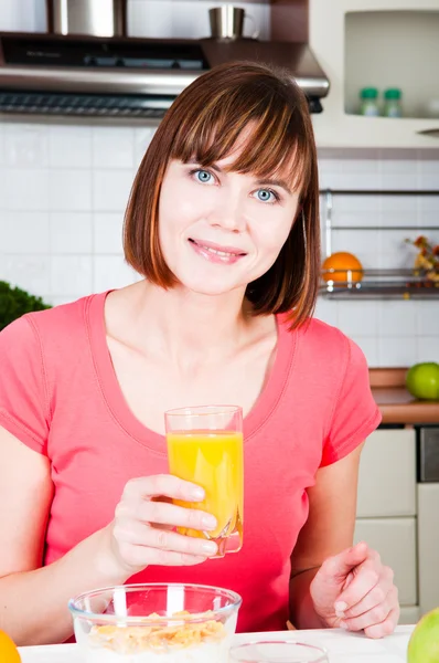 Mladá žena doma pít pomerančový džus — Stock fotografie