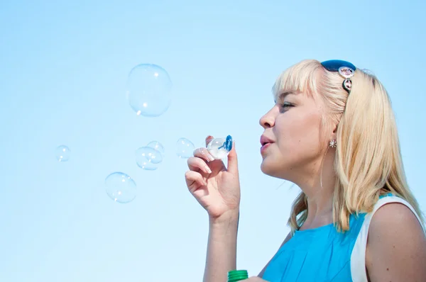 Schöne junge Frau pustet Seifenblasen — Stockfoto