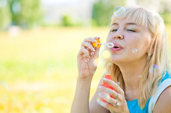 Woman blowing bubbles in park — Stock Photo, Image