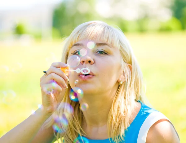 Woman blowing bubbles in park — Stock Photo, Image