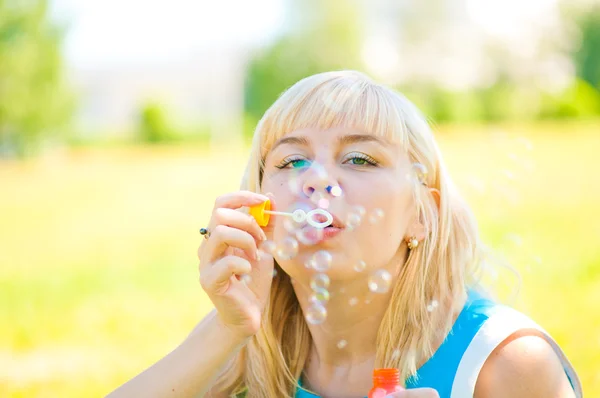 Žena foukání bublin v parku — Stock fotografie