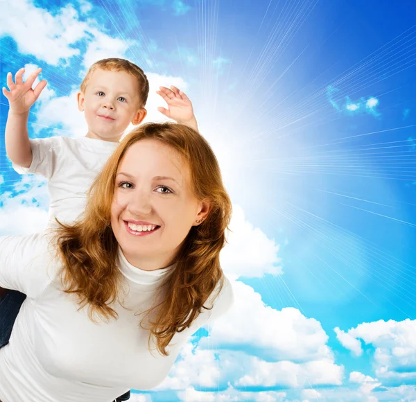 Vrouw en zoontje tegen blauwe hemel — Stockfoto