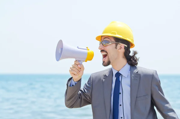 Man with hard hat and loudspeaker on beach — Stock Photo, Image